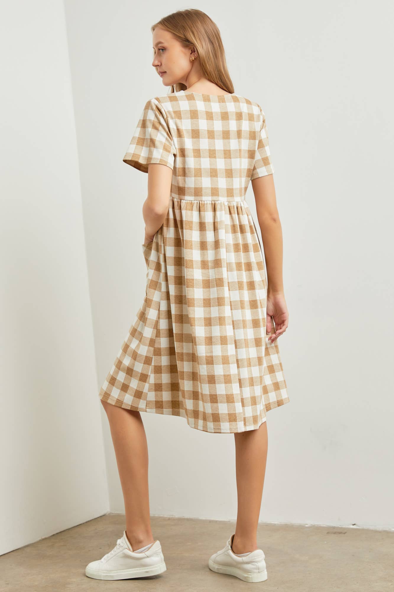 Woman wearing a checkered dress against a plain background