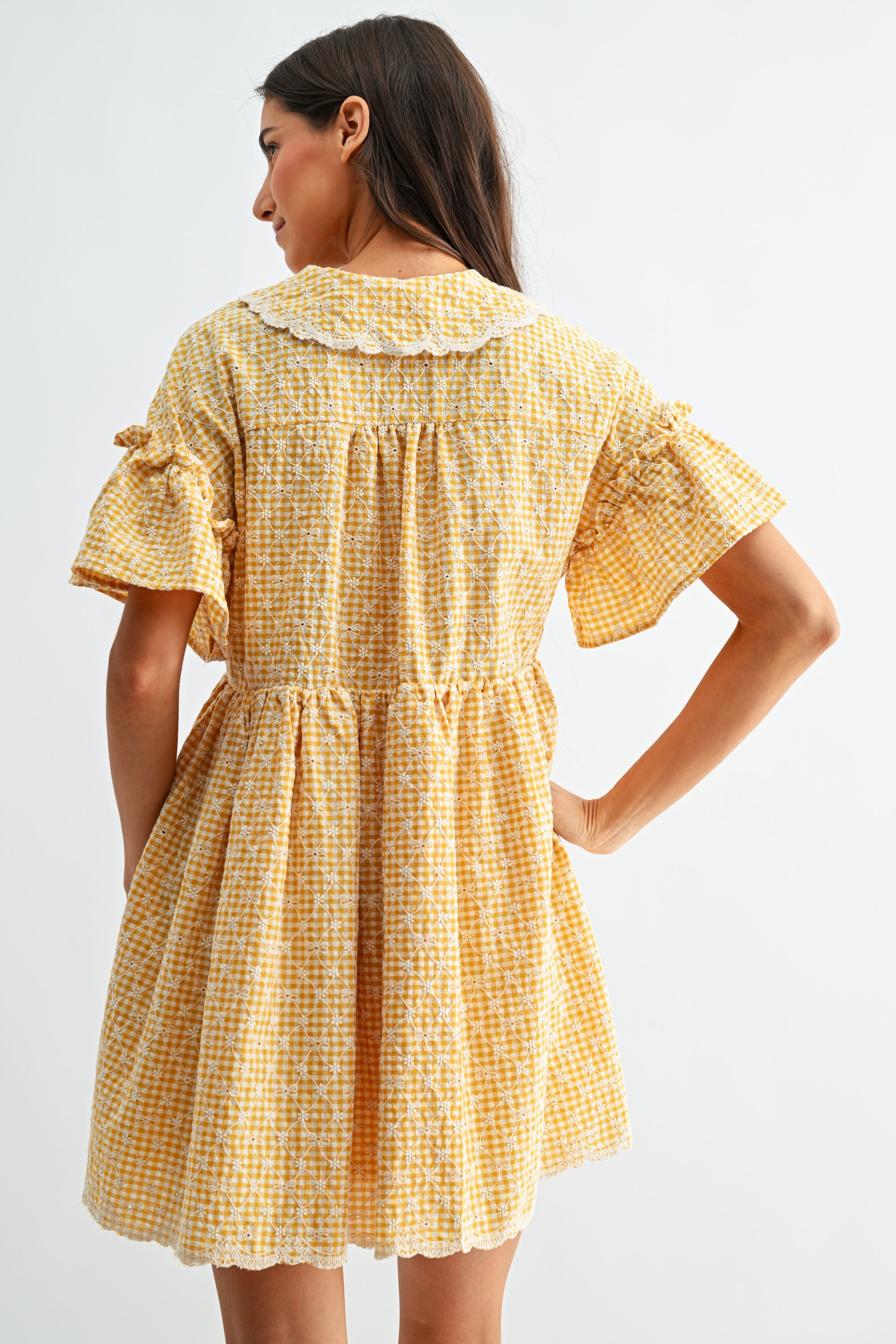 Woman wearing a yellow checkered dress on a white background